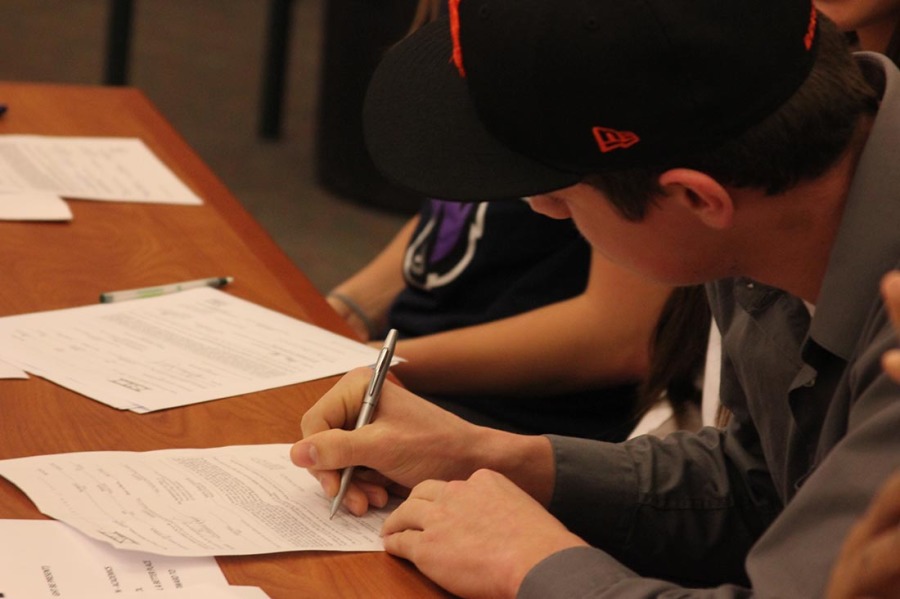 Football player Robert Kvinsland signing letter of intent to Idaho State University.