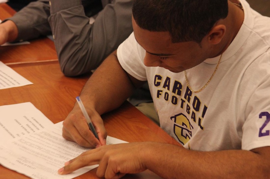 Football player Major Ali signing letter of intent to Carroll College.